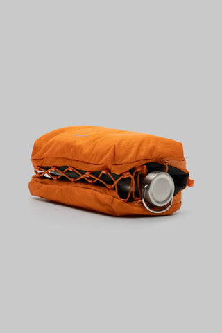 Orange grid sacoche bag laying down with water bottle inside