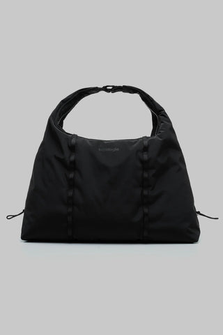 A black medium shoulder bag with a single top handle, featuring vertical loop details against a solid gray background.
