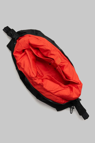 A top view of a black medium cloud hobo bag with a bright red interior lining on a light grey background