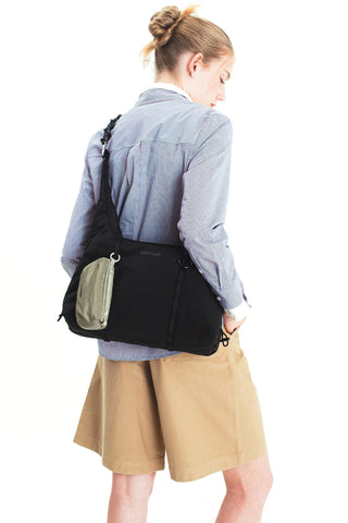 Person carrying Topologie small cloud hobo bag in black with green pouched attached