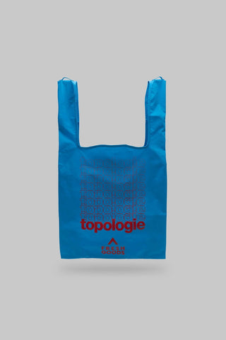 Blue reusable shopping bag with 'topologie' branding on a gray background
