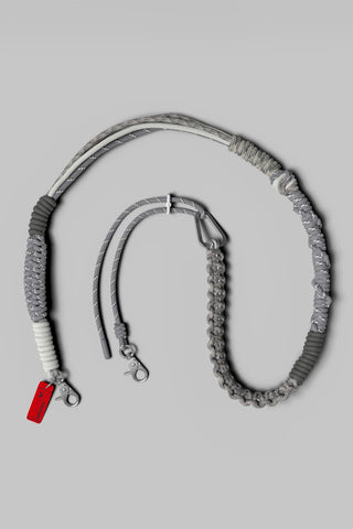 A bag shoulder strap with braided rope and multiple shaded of grey, displayed on a light grey background