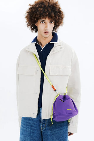 Person wearing a white jacket with a purple bag over their shoulder on a white background