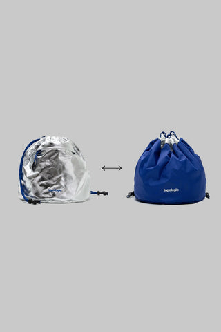 Two drawstring bags, one silver and one blue, on a gray background.
