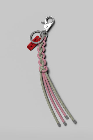 A pale green and pink woven rope keychain with silver hardware on a light grey background