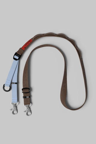 A brown and light blue bag strap with silver metal clips displayed on a neutral gray background.