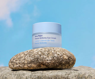 Ursa Major Forest Alchemy Eye Cream jar on a rock with a blue sky background