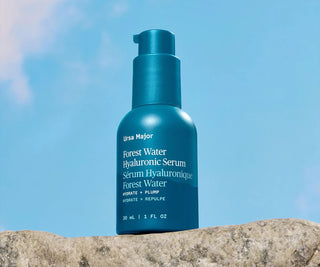Blue bottle of Ursa Major Forest Water Hyaluronic Serum against a clear blue sky.