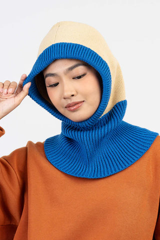Person wearing a blue and beige knitted hood against a white background