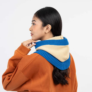 Person wearing a blue and beige knitted hood on a white background