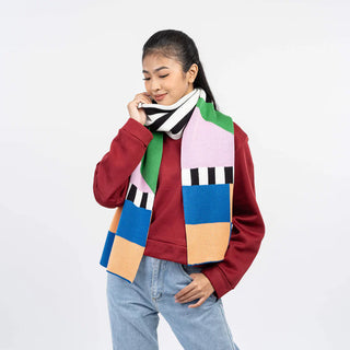 Person wearing a colorful patchwork scarf with a plain background