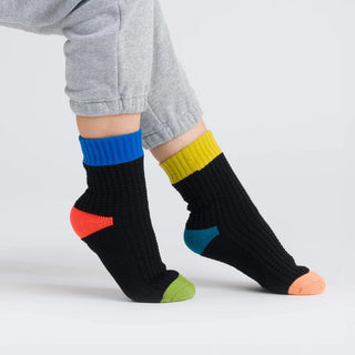 Colorful socks with geometric patterns worn by a person on a light gray background