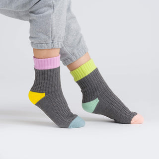 Gray socks with colorful accents worn by a person on a light gray background