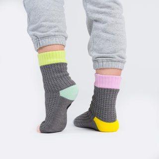 Gray socks with colorful accents worn by a person on a white background