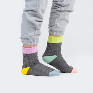 Gray socks with colorful accents worn by a person in gray pants on a white background