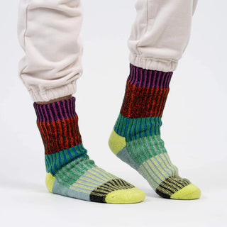 Colorful striped socks worn with light-colored pants on a white background