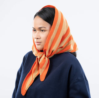 Woman wearing an orange and beige striped headscarf on a white background