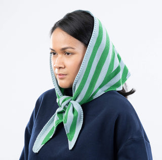 Person wearing a green and white striped headscarf on a plain background