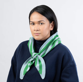 Woman wearing a green and white striped scarf against a plain background