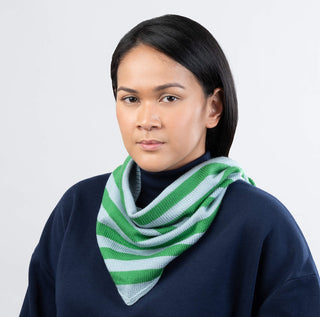 Woman wearing a green and white striped scarf against a plain background