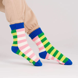Colorful striped socks worn with beige pants on a light gray background