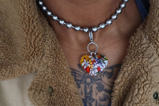 Person wearing jacket with thick ball chain and millefiori heart shaped pendant