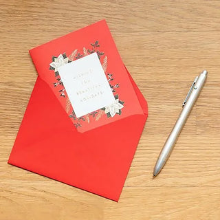 Red envelope with a card and a pen on a wooden surface