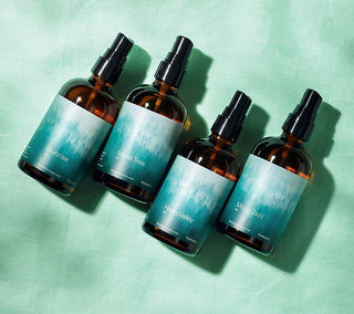 Four brown spray bottles with blue labels on a green background