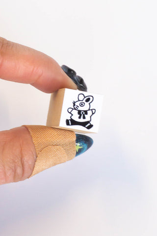 Two fingers holding stamp of illustrated bunny jumping