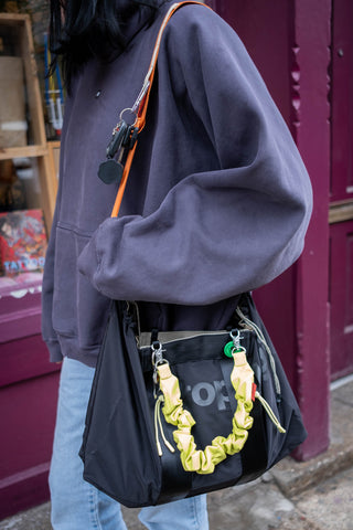 Person wearing a dark gray hoodie with a black bag featuring yellow accents.