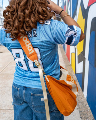 Person wearing a blue sports jersey with visible branding, standing in front of a colorful mural.