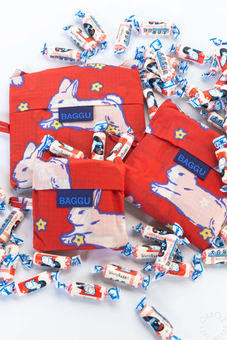 Red reusable bags with rabbit design and 'Baggu' branding surrounded by small packages on a white background.