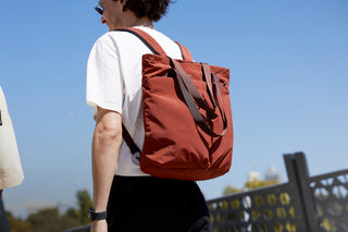 Person wearing a red backpack against a clear blue sky