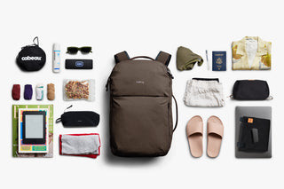 Collection of travel items including a backpack, sunglasses, toiletries, and clothing on a white background.