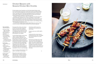 Chicken skewers with sesame chicken skin crumbs on a plate with a glass of beer and small bowl.