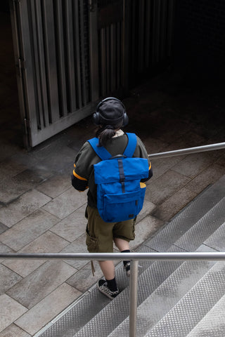 Person with a blue backpack walking down stairs in an urban setting