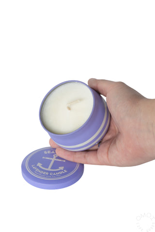 Hand holding a lavender sea salt candle on a white background