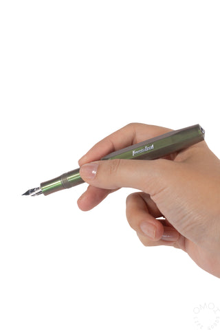 A hand holding a shadow green fountain pen with a silver nib against a plain white background.