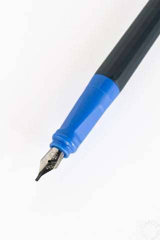 Close-up of a fountain pen nib with a blue grip, black barrel on a white background.