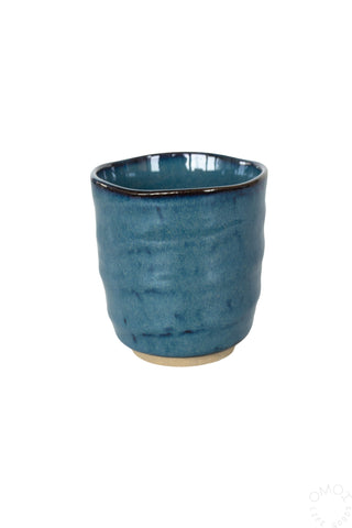 Dark blue glazed ceramic teacup on a white background