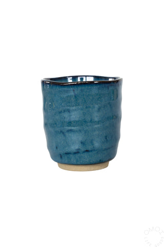 Front view of dark blue glazed ceramic teacup on a white background
