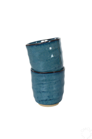 Two stacked dark blue glazed ceramic teacups on a white background