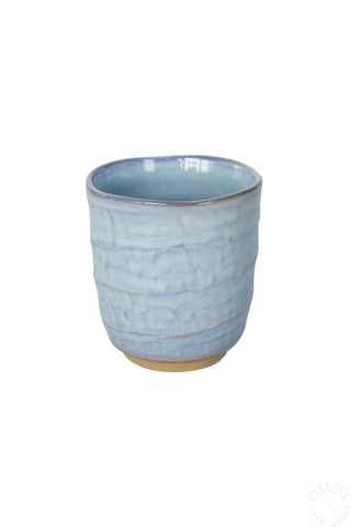 Light blue glazed ceramic teacup on a white background