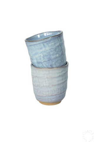 Two stacked light blue glazed ceramic cups on a white background