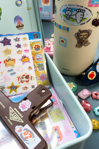 Collection of sticker sheets on a light blue toolbox with a water bottle