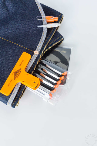 Medium denim Luddite pouch with orange clamp and pens on a white background