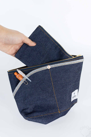 Medium denim Luddite pouch with hand holding inner zippered pocket on a white background