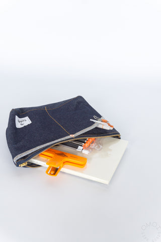 Medium denim Luddite pouch on the side and open with notebooks on a white background