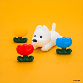 White dog figurine with colorful flower-like bases on a yellow background