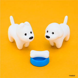 Two white dog figurines with a blue bowl and bone on an orange background